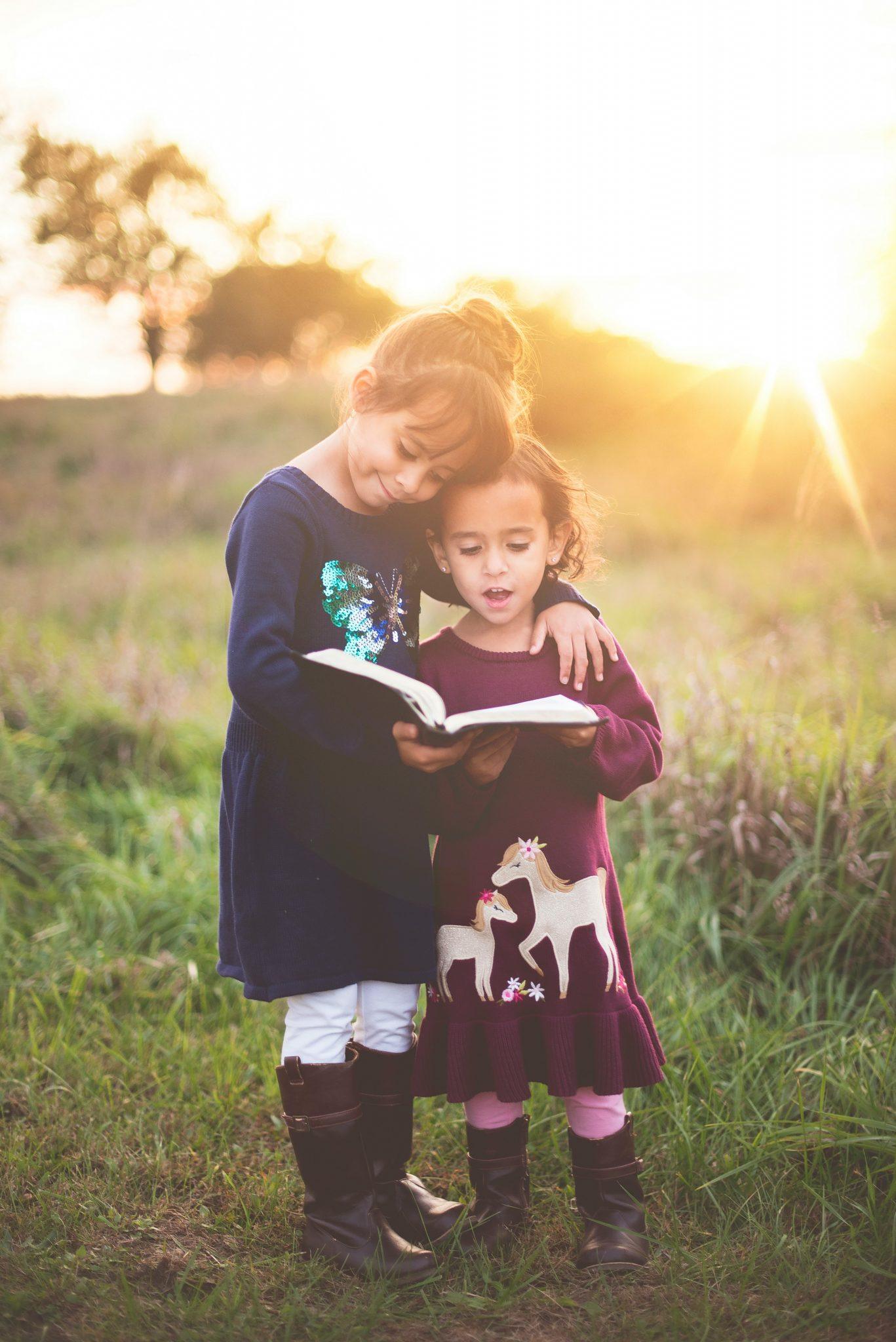 Dos niñas leyendo juntas al aire libre