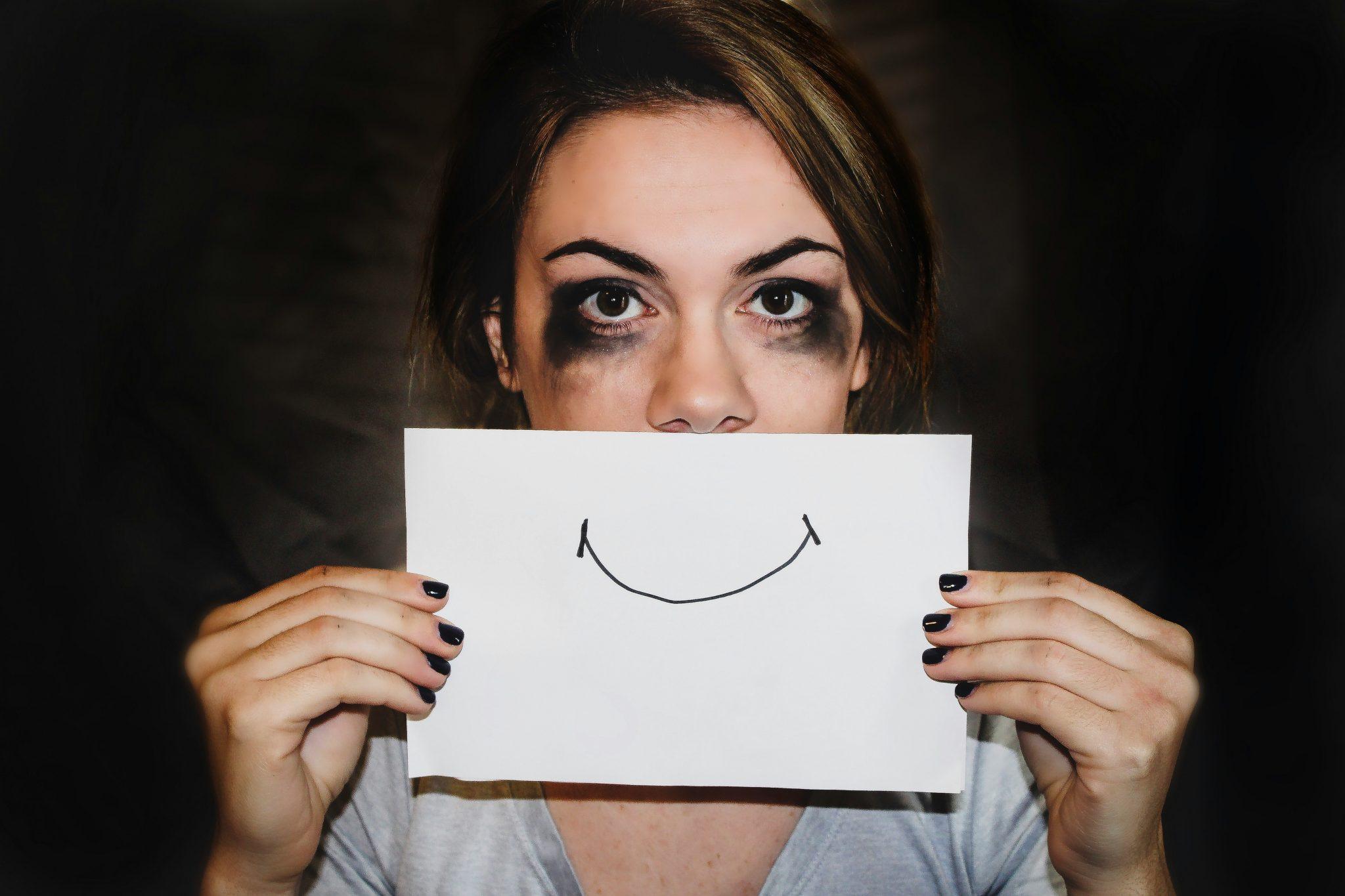 Mujer sosteniendo un papel con una sonrisa dibujada