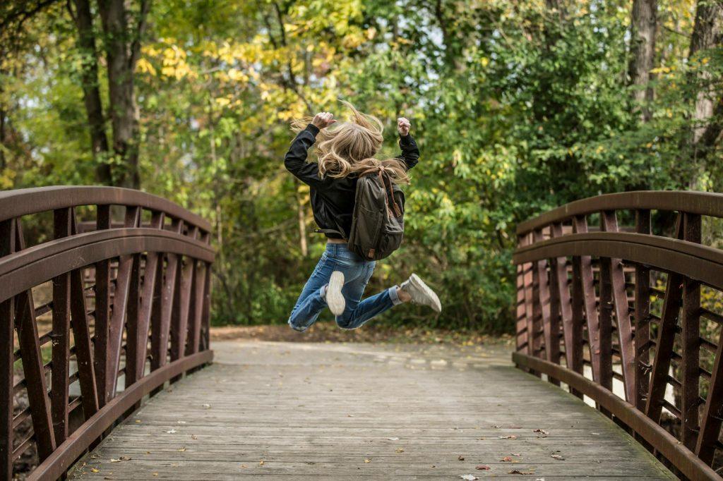 Niña saltando en un camino de bosque