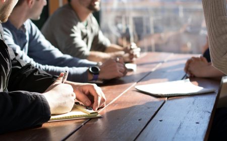 Grupo de personas participando en un taller formativo, tomando notas en una mesa de madera